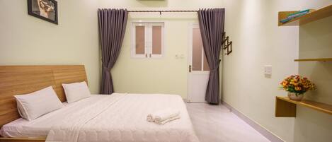 A bedroom with a wooden bed, a white mattress, and a beige wall.