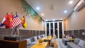 A restaurant with a long counter, multiple seating options including booths and tables, and a decorative wall with flags. - Language Exchange Hostel 1 (Ho Chi Minh City)