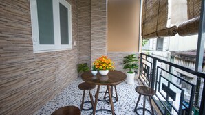 A small balcony with a tiled floor, a round table with stools, and potted plants. - Language Exchange Hostel 1 (Ho Chi Minh City)