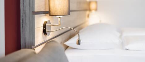 Ein modernes Bett mit Holz-Kopfteil und einer Wandlampe.