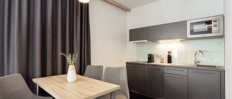 Una cocina moderna con microondas, lavabo y armarios. Hay una mesa de comedor con sillas y un jarrón con flores.