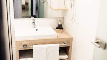 A bathroom with a white sink, wooden vanity, a towel rack, and a mirror.