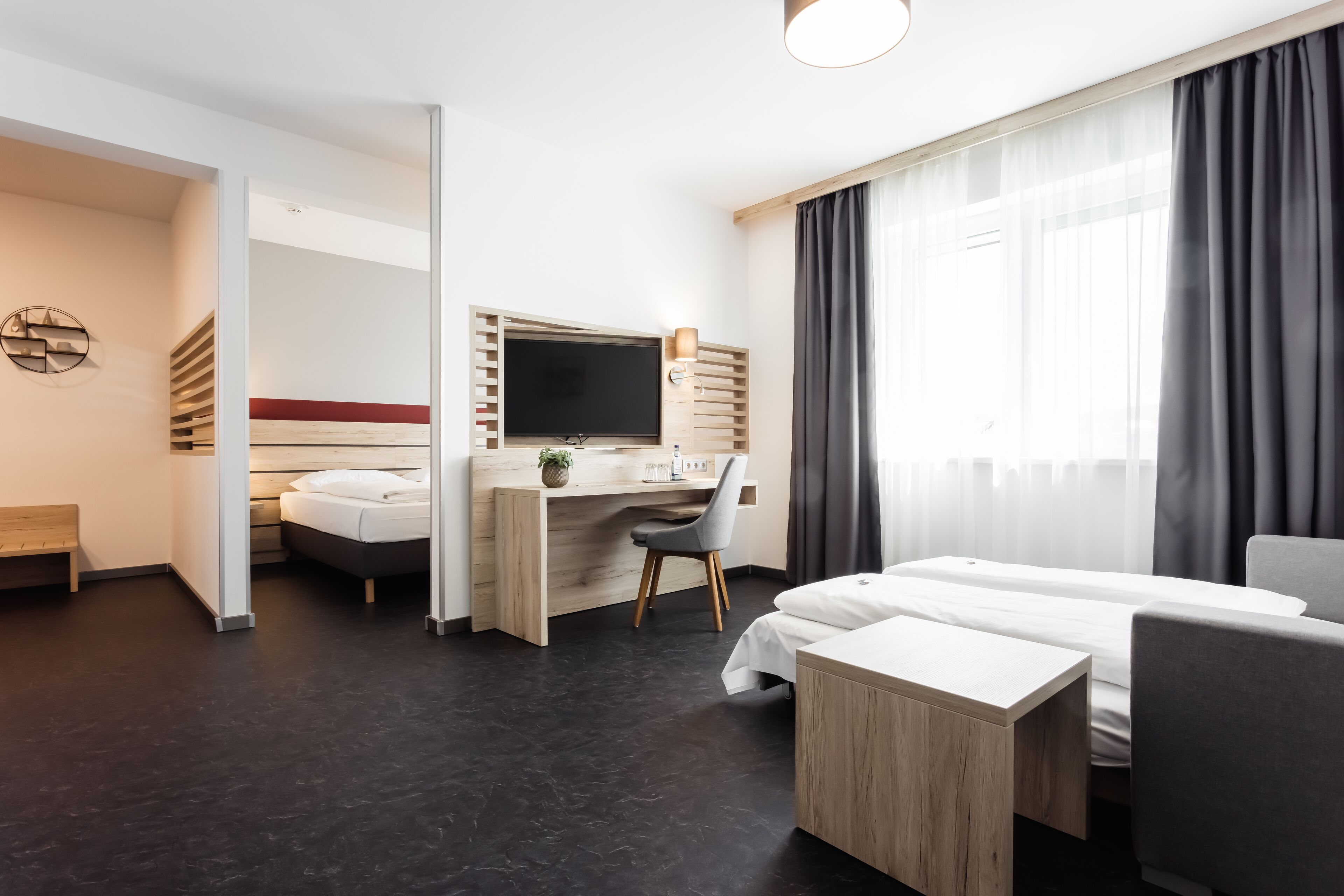 Una habitación de hotel moderna con una cama, un escritorio con ordenador, una silla y un televisor.