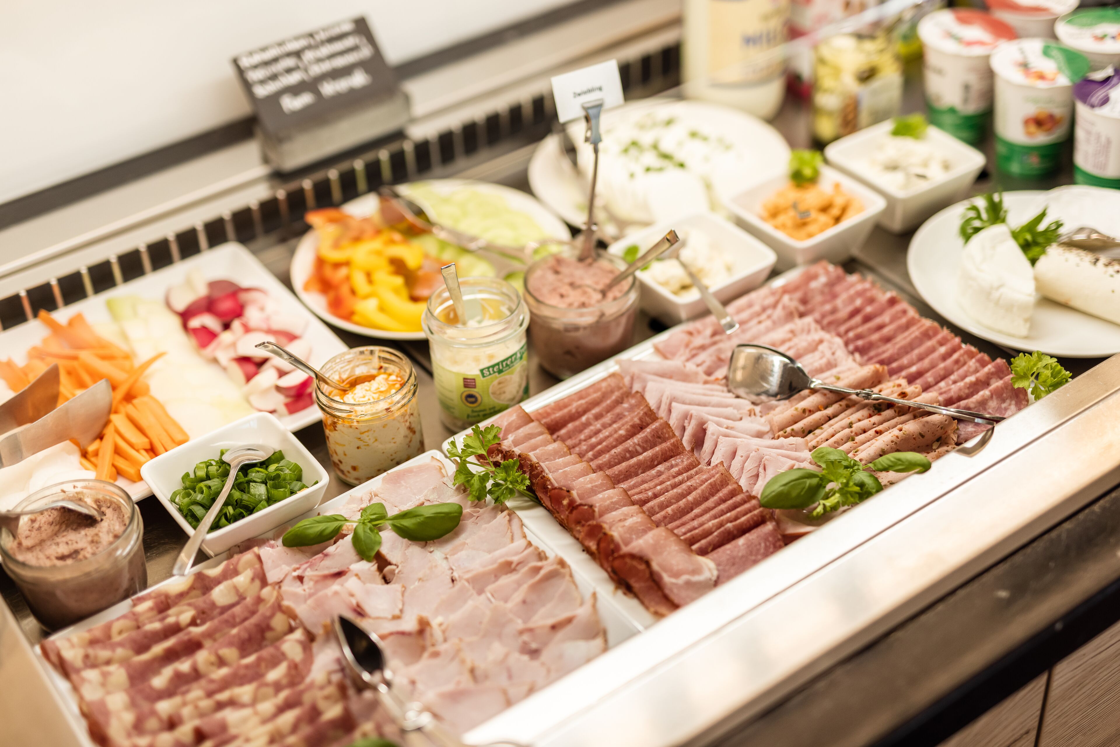 A buffet with various food items including meats, cheeses, and salads.