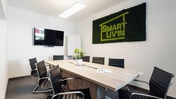 Et mødelokale med et langt bord, seks stole, et fladskærms-tv og et 'SMART LIVIN'-skilt på væggen.