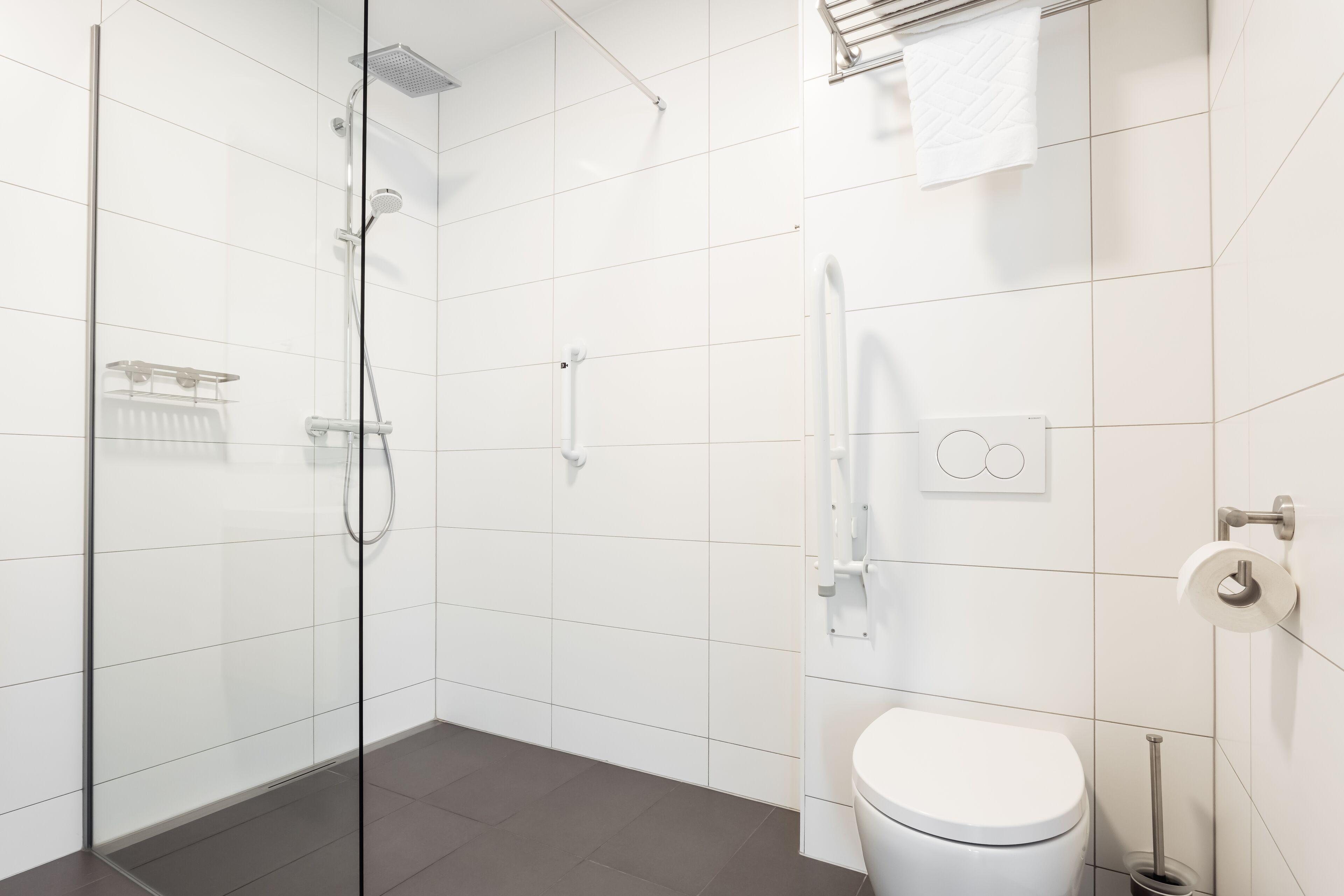 A modern bathroom with a glass-enclosed shower, a white toilet, and a towel rack.