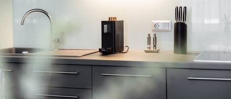 A modern kitchen with a stainless steel sink, a coffee machine, and a knife block.