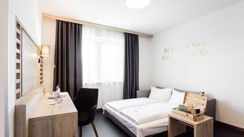Habitación de hotel con cama, escritorio, silla, mesita de noche y una pared con una cita.