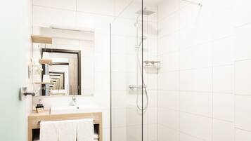 Un bagno moderno con doccia vetro, lavabo e specchio, e un WC.