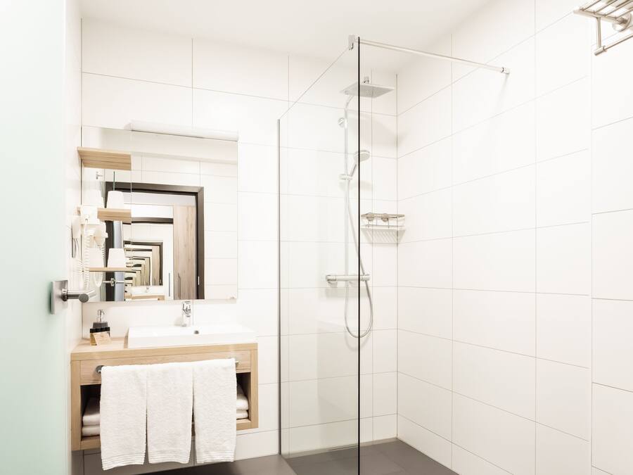 Un bagno moderno con doccia vetro, lavabo e specchio, e un WC.