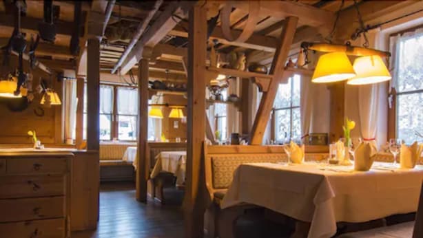 A rustic wooden interior with exposed beams, a dining area with a table set for two, and a bench. - Hotel Höhengasthof Grüner Baum (Feldberg)
