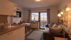 A compact living space with a kitchenette, a dining area, and a seating area with a sofa and a lamp. - Hotel Höhengasthof Grüner Baum (Feldberg)
