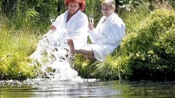 Dos personas sentadas junto al agua, una sosteniendo un vaso.