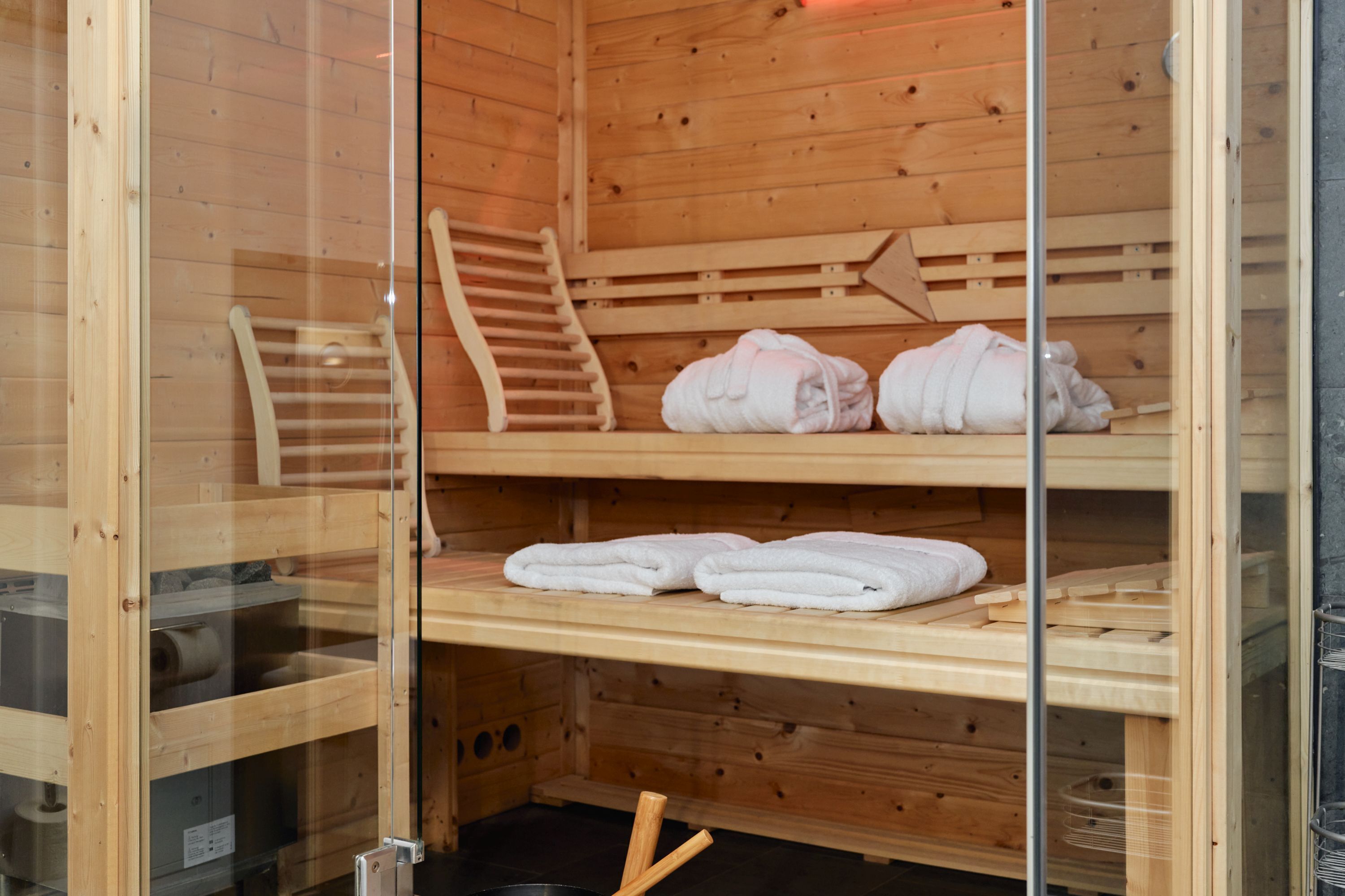 Ein Sauna-Raum mit Holzbänken, einem Handtuchhalter und ordentlich gefalteten Handtüchern auf Regalen.