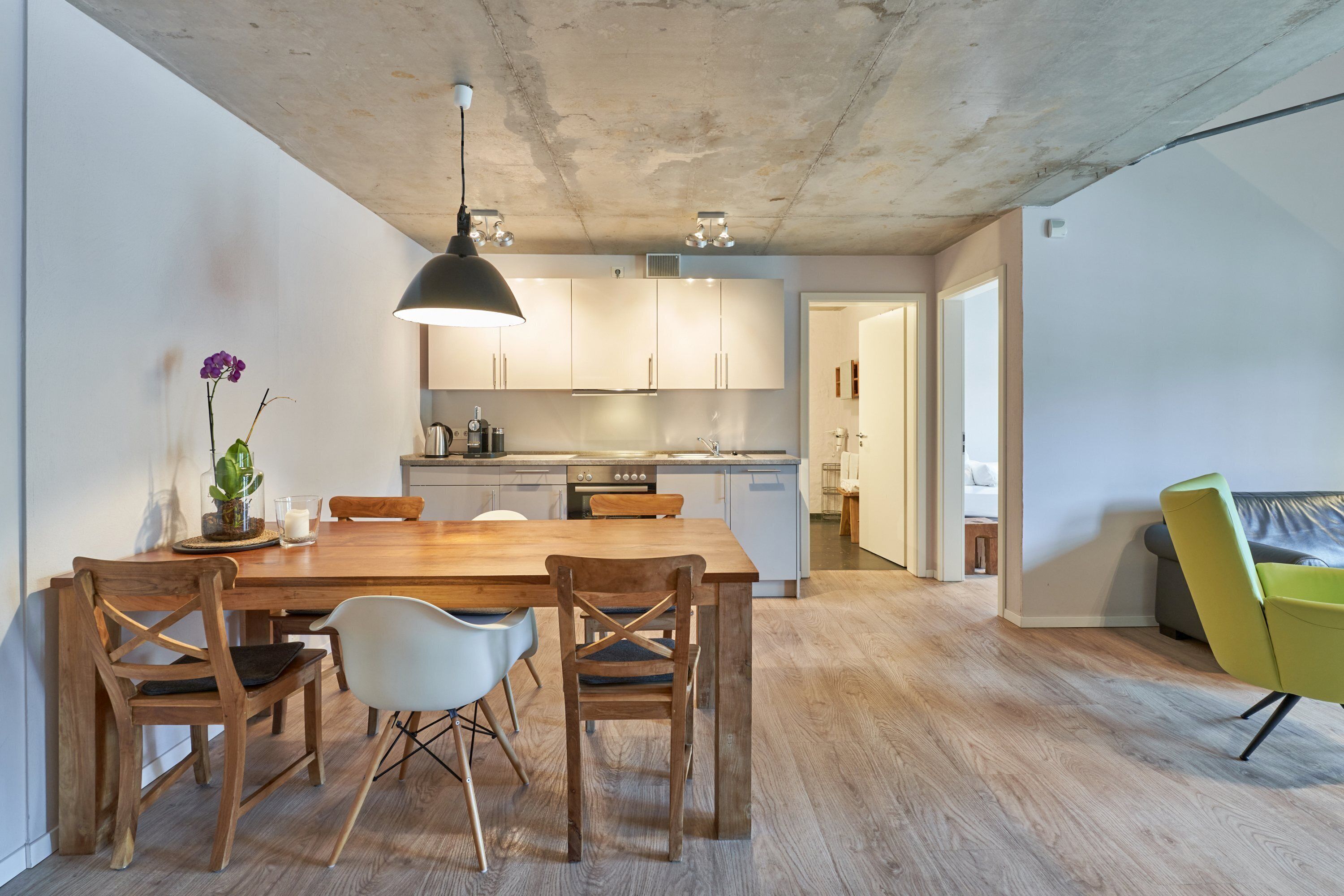 Une cuisine moderne avec des meubles en bois, une table à manger avec des chaises et un luminaire suspendu.