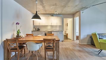 Une cuisine moderne avec des meubles en bois, une table à manger avec des chaises et un luminaire suspendu.