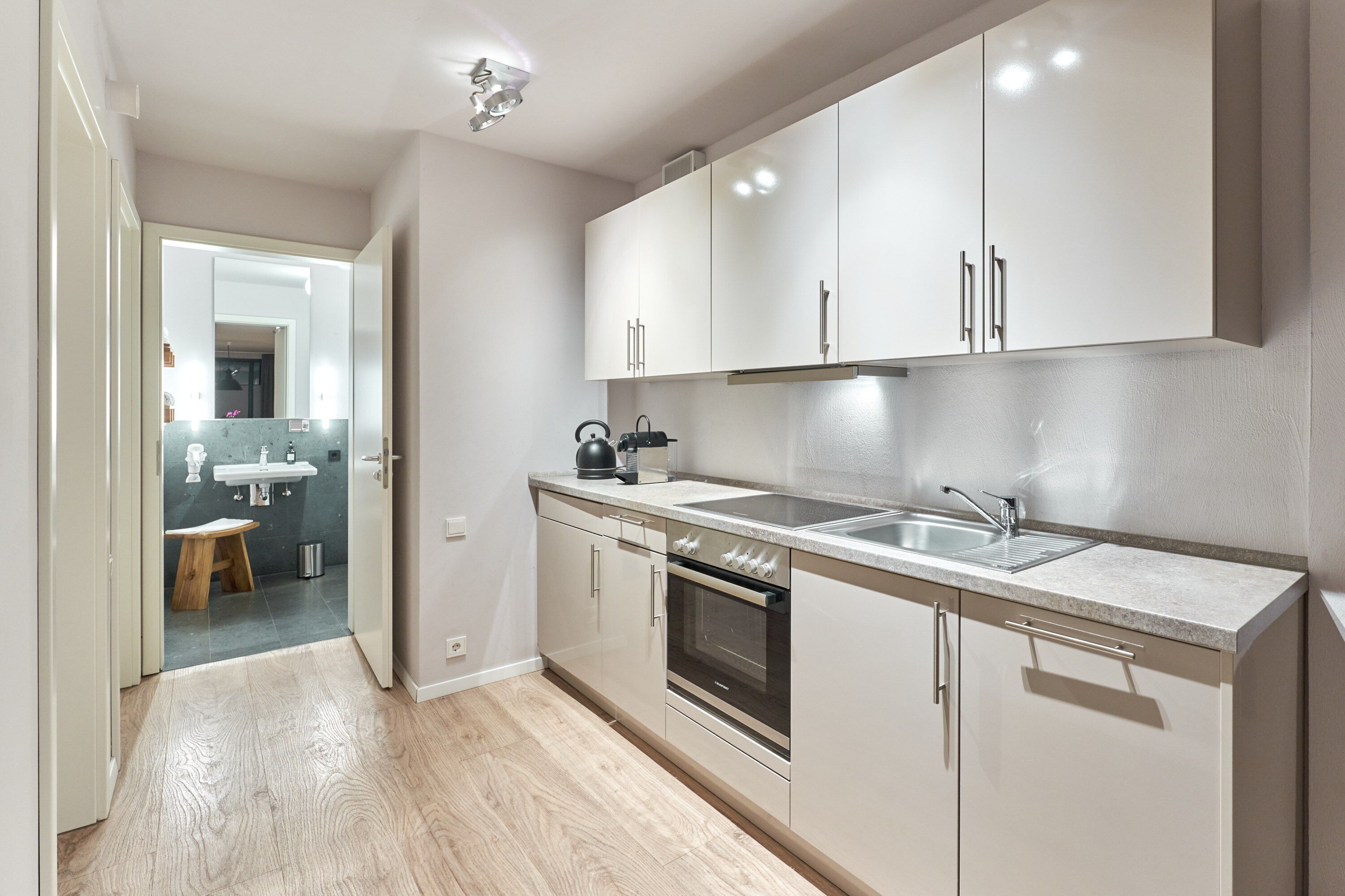 A modern kitchen with white cabinets, a stainless steel sink, and a built-in oven.