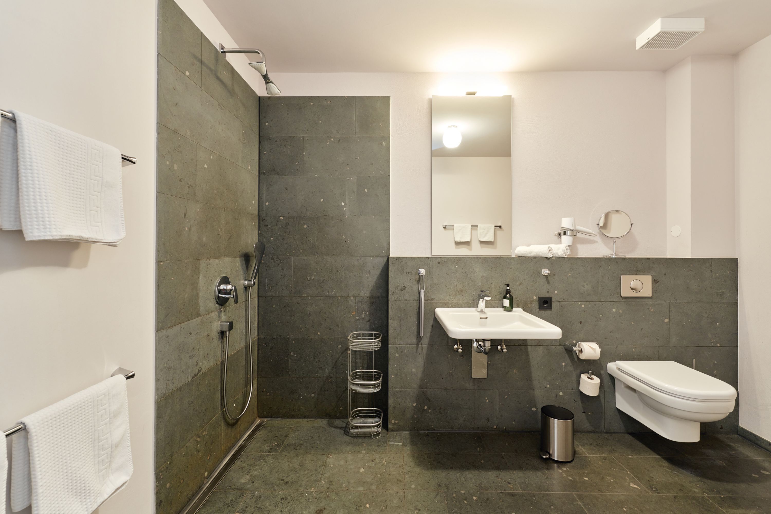 A modern bathroom with a shower, sink, toilet, and a mirror.