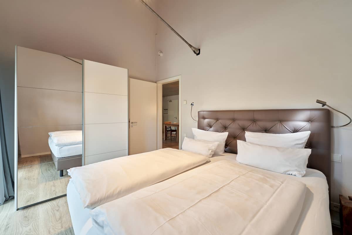 A bedroom with a large bed, a wardrobe, and a mirror.