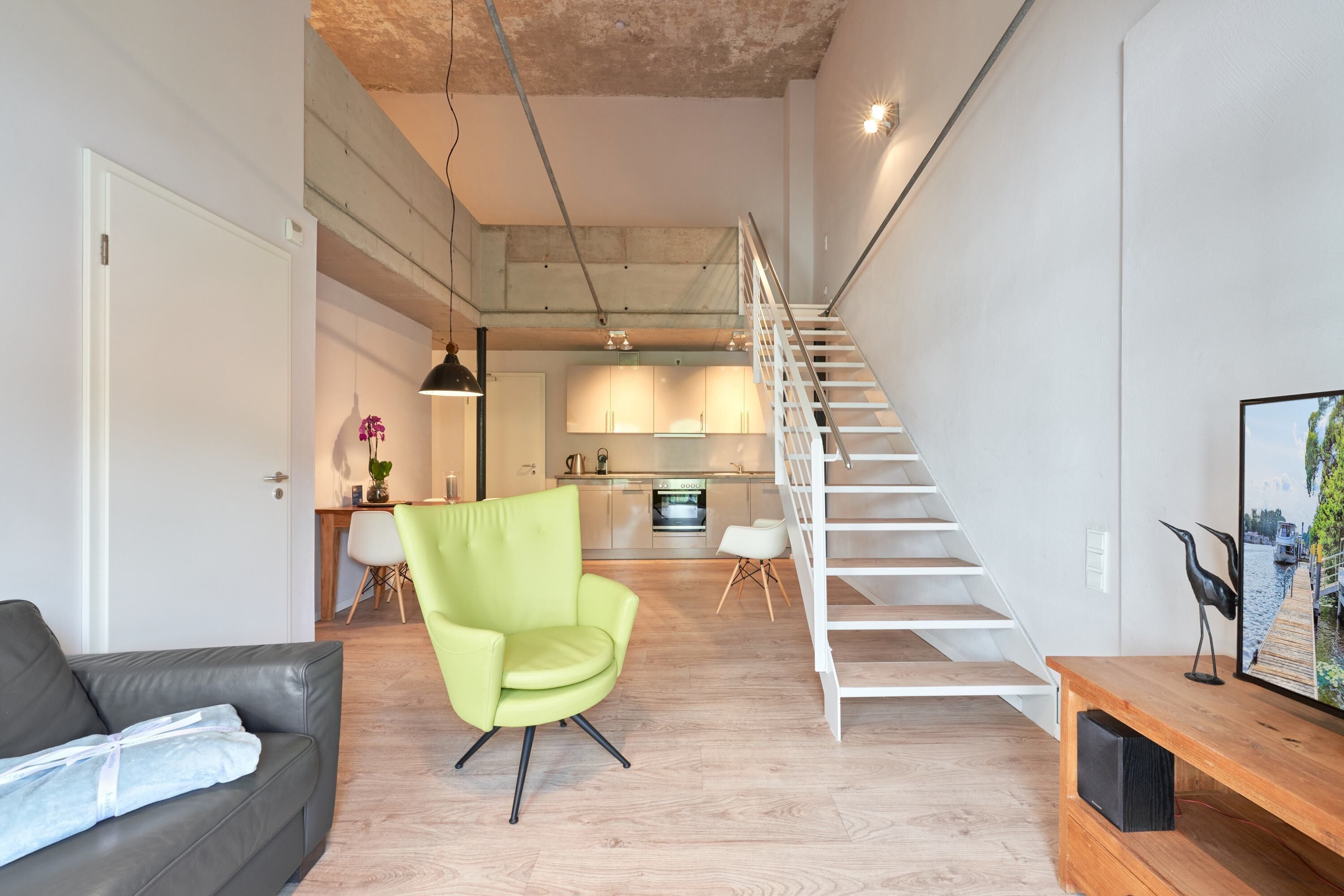 A modern living space with a staircase, a dining area, and a kitchen.