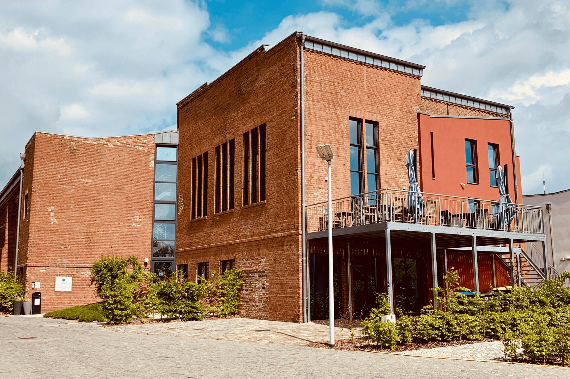Un edificio moderno con fachada de ladrillo, ventanas grandes y un balcón con mobiliario exterior.