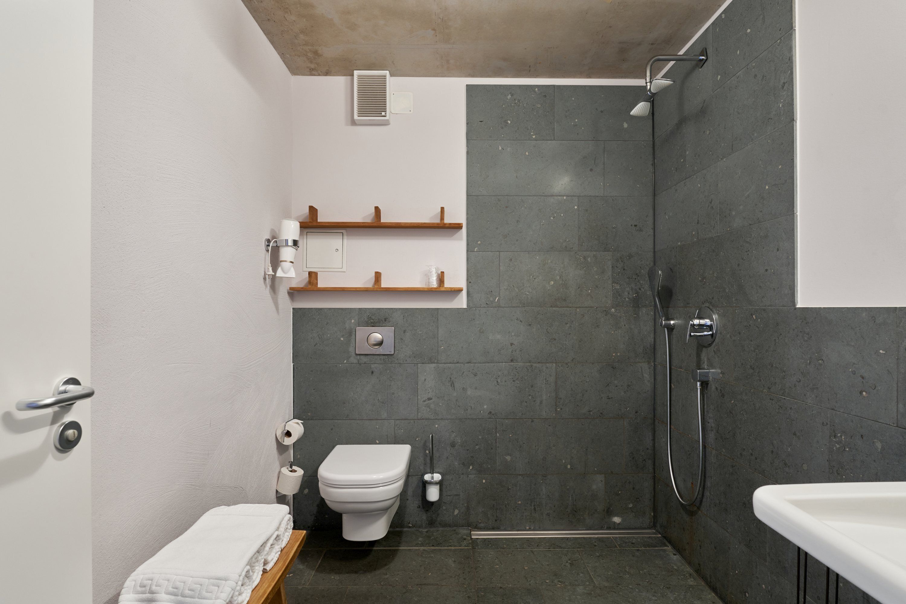 A modern bathroom with a shower, toilet, and sink.