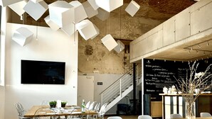 A modern interior with hanging geometric light fixtures, a staircase, and a chalkboard menu. - havelblau FERIENLOFTS (Brandenburg an der Havel)