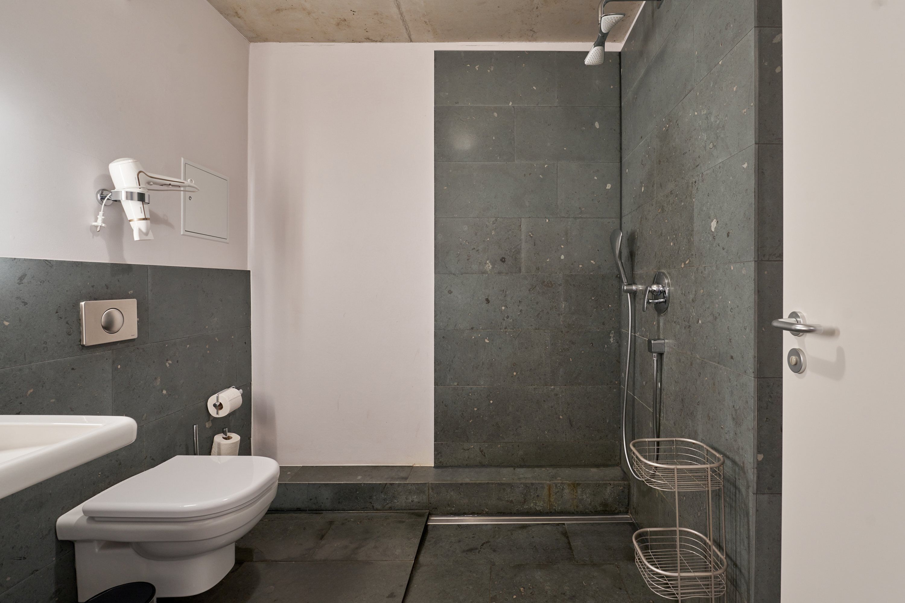 A modern bathroom with a toilet, sink, and shower.