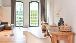 A modern living room with a sofa, a wooden table with a woven basket, and a vase with dried flowers. - havelblau FERIENLOFTS (Brandenburg an der Havel)