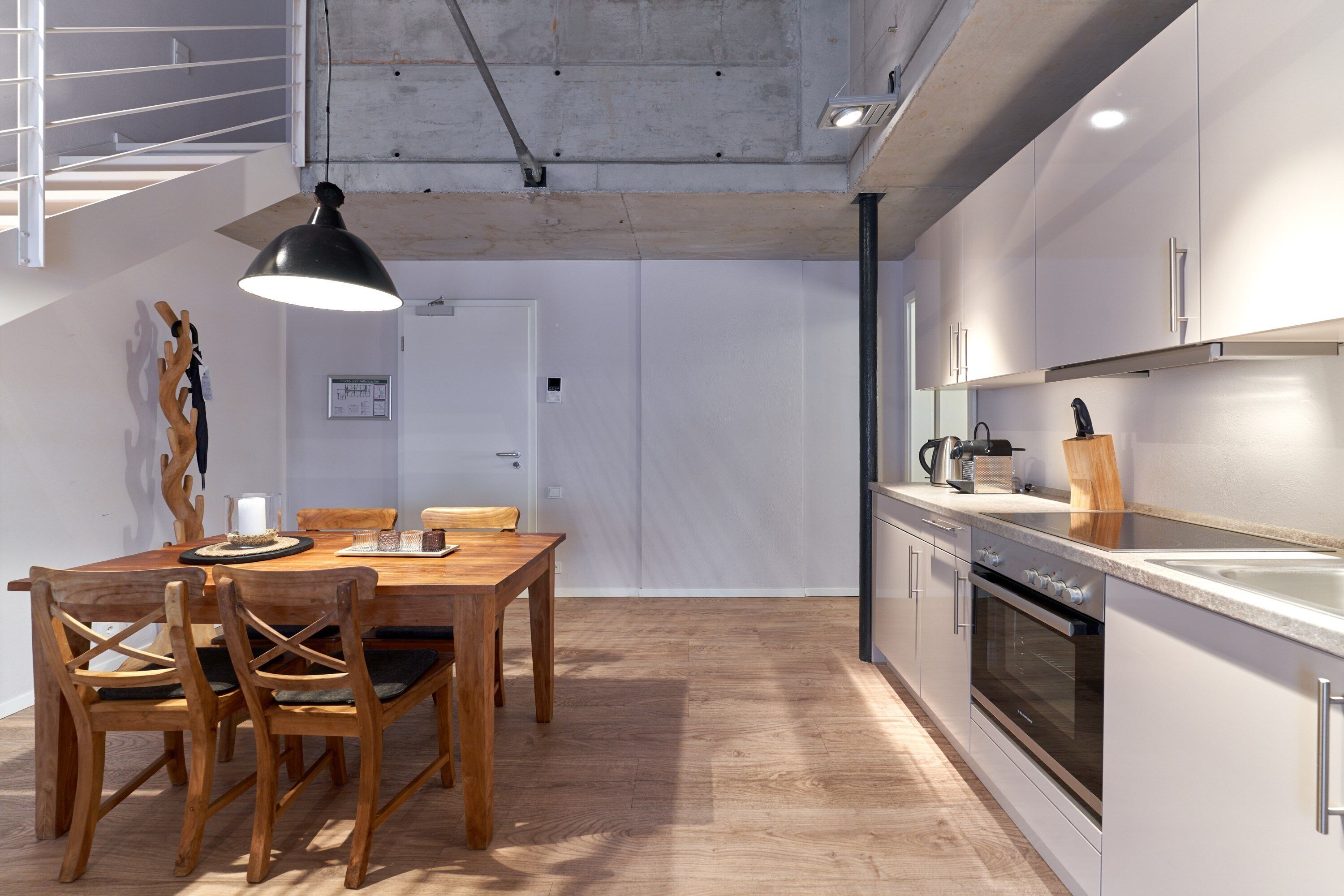 A modern kitchen with white cabinets, a wooden dining table, and a large pendant light.