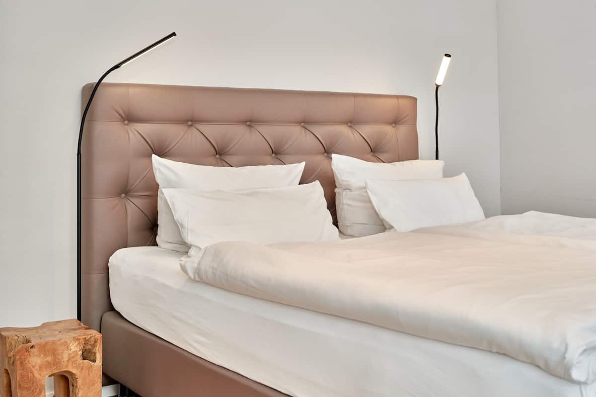 A neatly made bed with a tufted headboard and two bedside lamps.