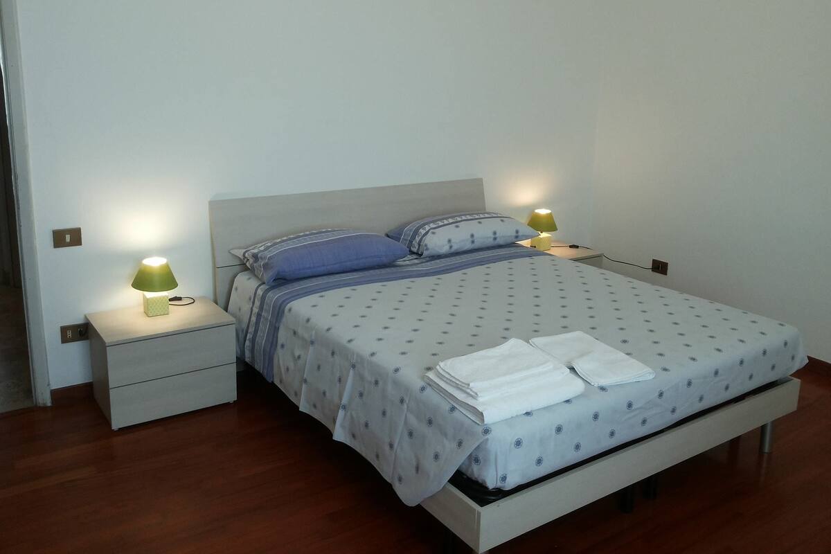 Un lit bien fait, avec une couvre-lit à motifs, deux oreillers et deux lampes de chevet.