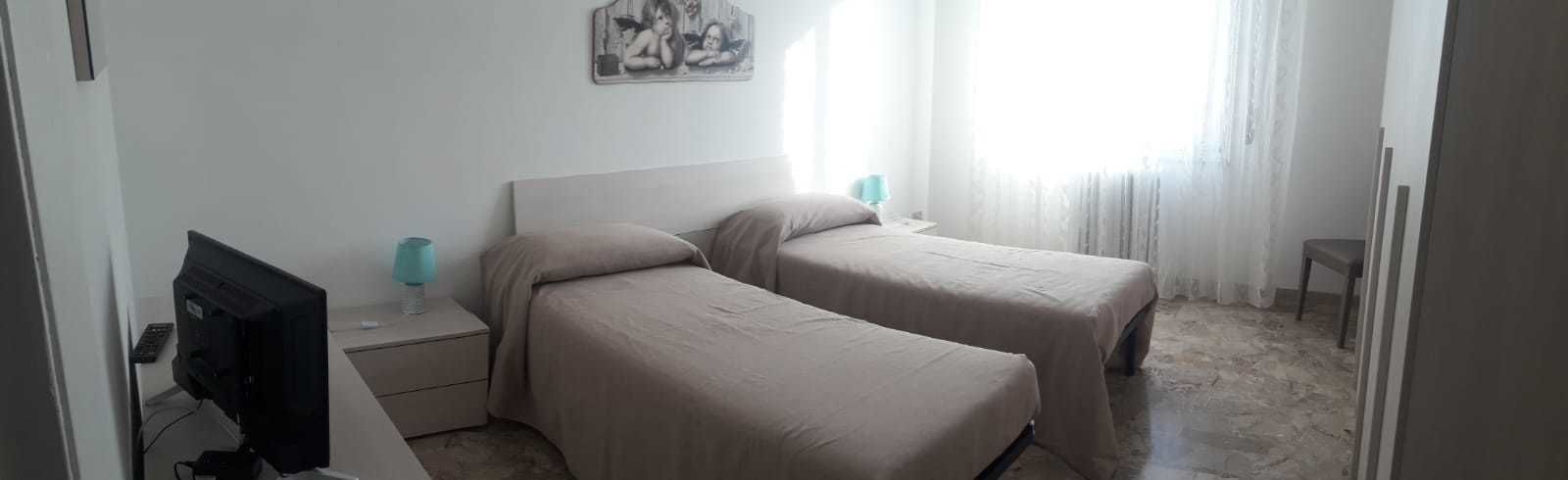 A hotel room with two beds, a TV, and a painting on the wall.