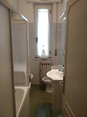A narrow bathroom with a bathtub, toilet, and sink. - Santo Spirito 2 (Arezzo)