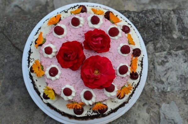 A round cake with red roses and small flowers on a white plate.