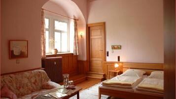 Una habitación acogedora con una cama de madera, un sofá, una mesita y una ventana con cortinas.