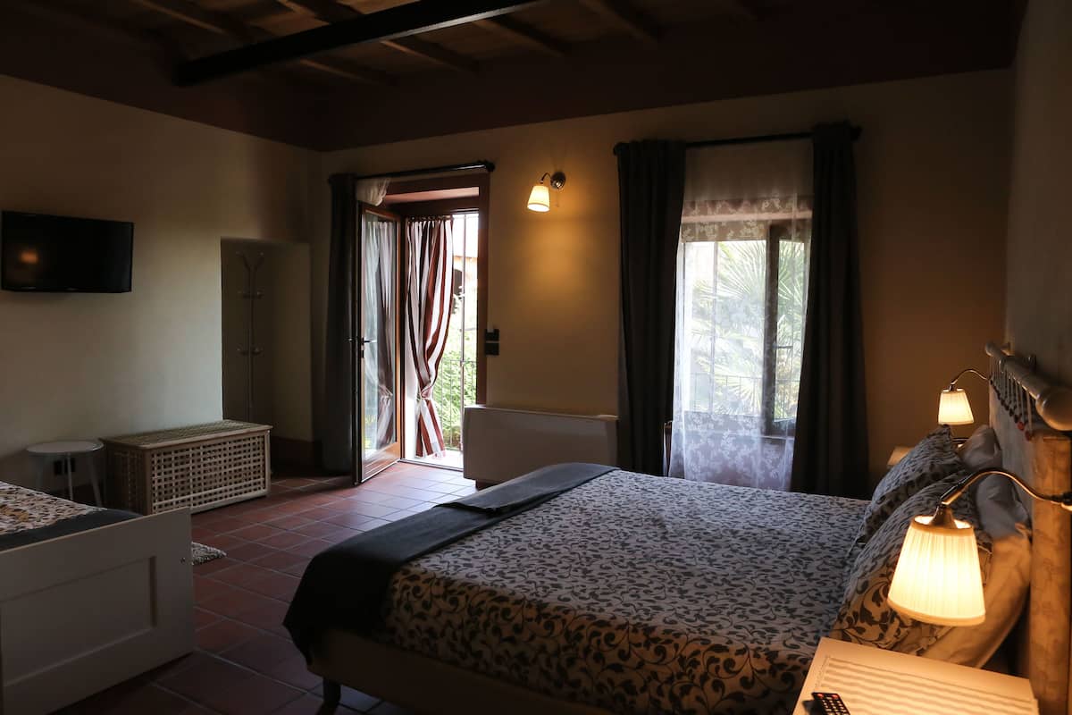 A bedroom with a bed, bedside table, lamp, and a television on the wall.