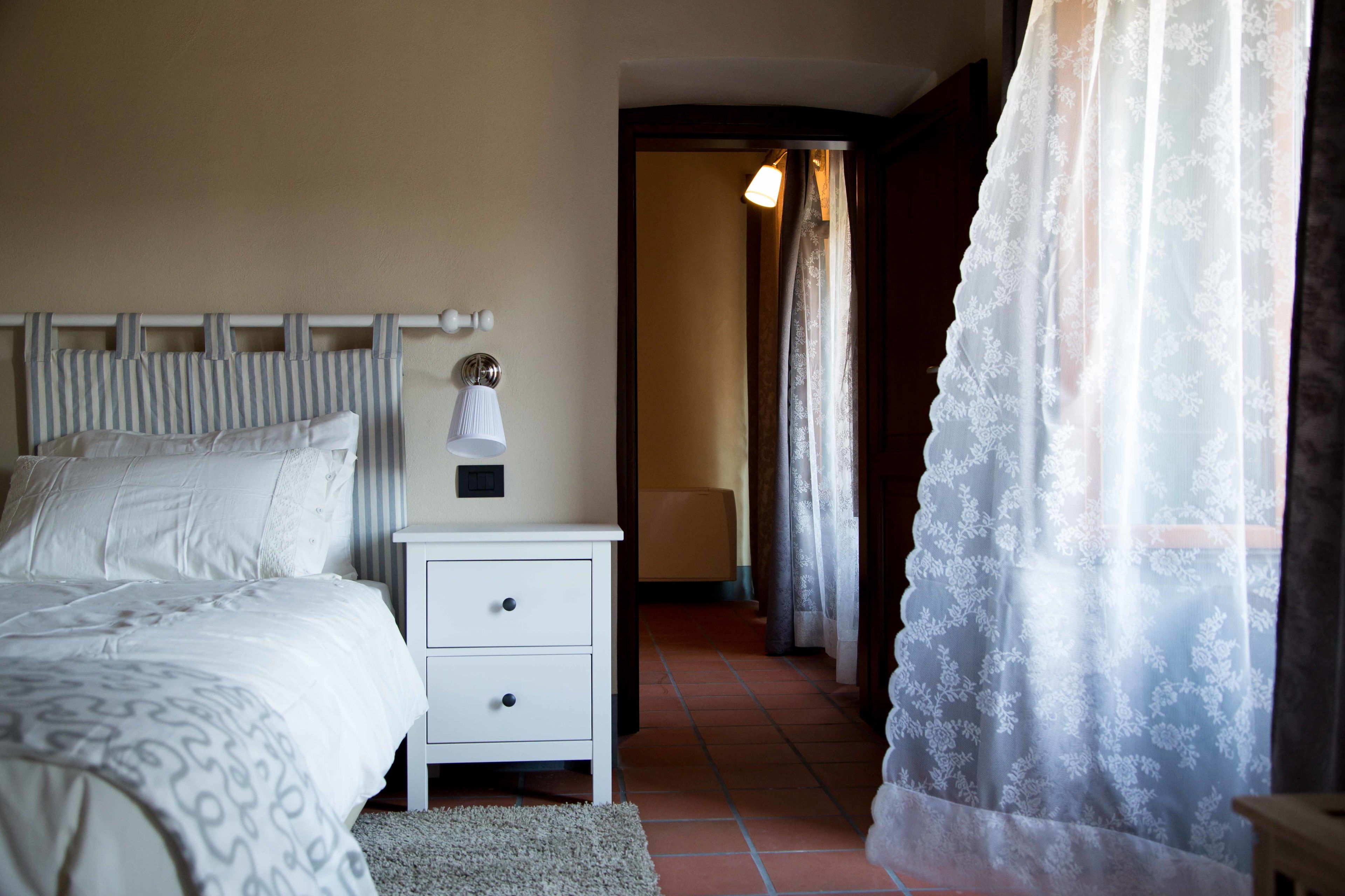 Un dormitorio con cama, mesita de noche, lámpara y puerta que da a otra habitación.