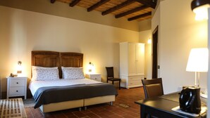 Un dormitorio con cama, mesitas de noche, una silla, una mesa y un armario.
