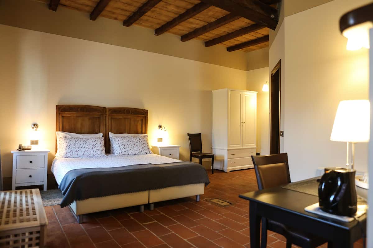 A bedroom with a bed, bedside tables, a chair, a table, and a wardrobe.