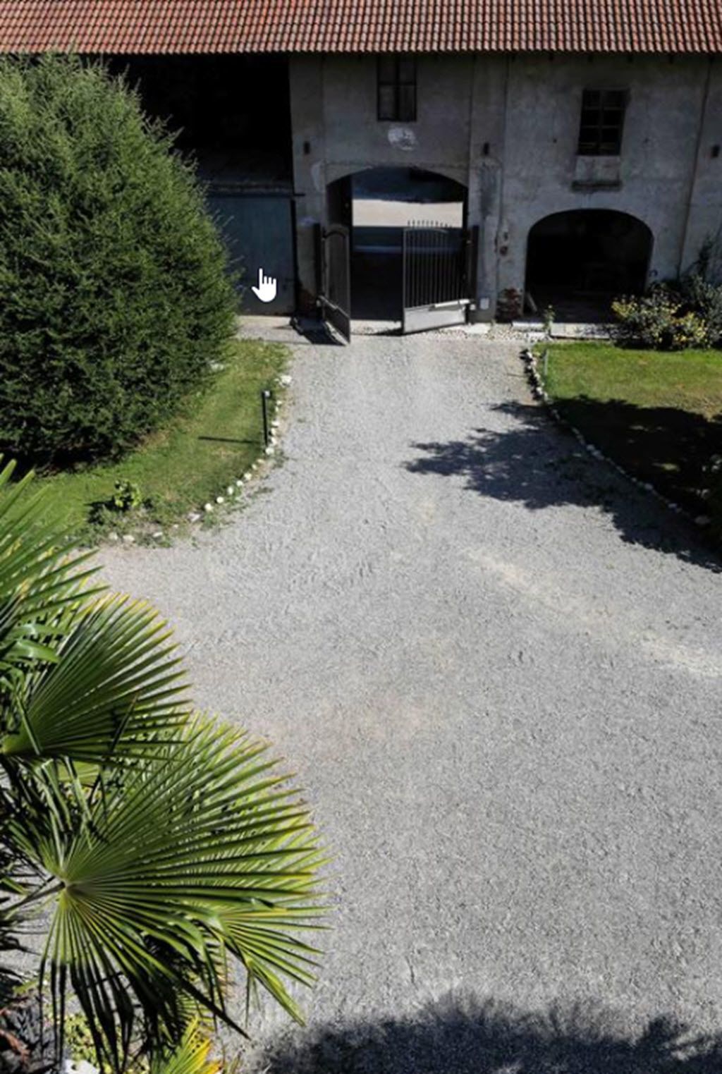 Un vialetto che conduce a un edificio con tetto in tegole e ingresso carrabile.