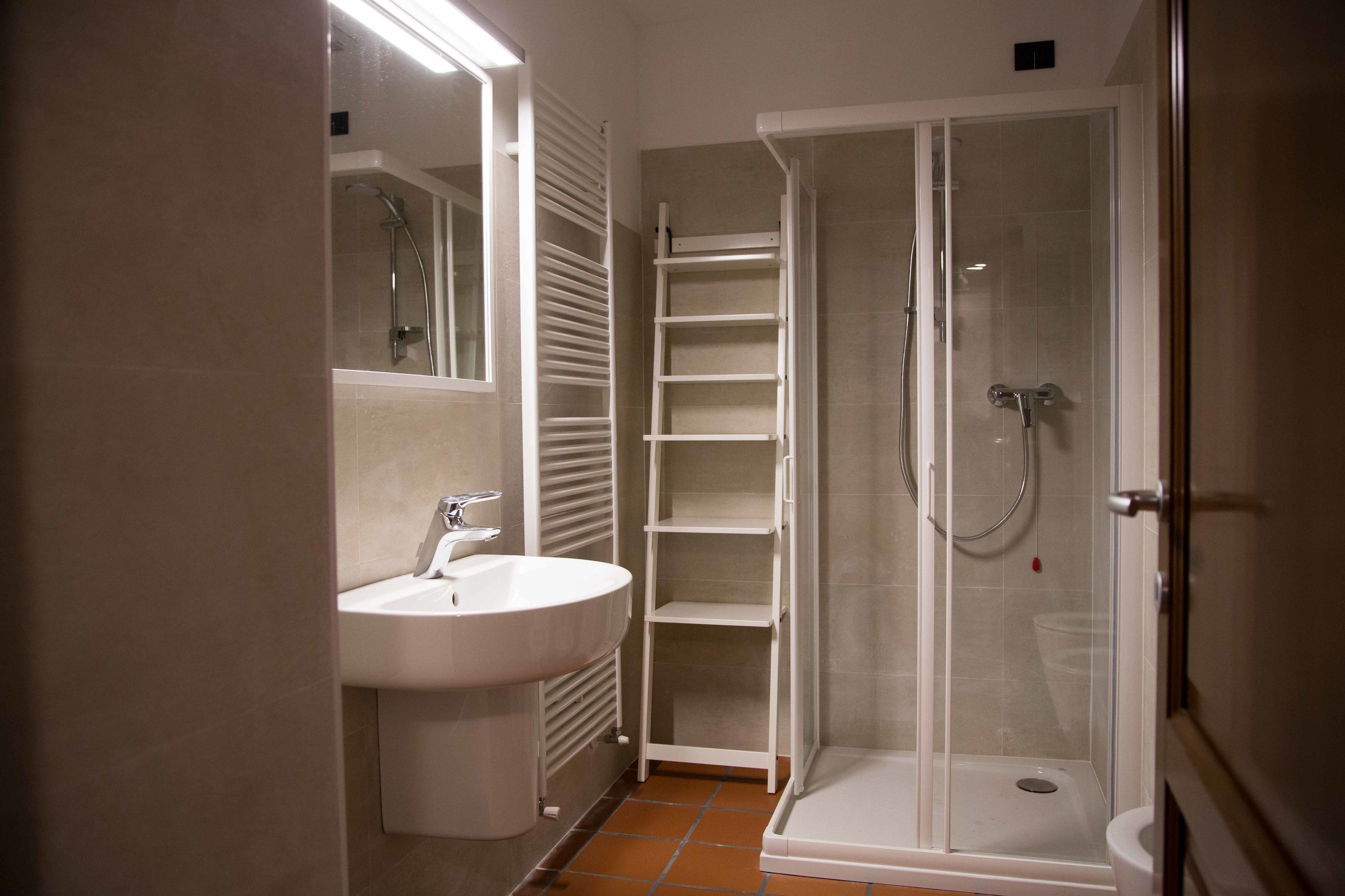 Un bagno con lavandino, specchio e cabina doccia in vetro.