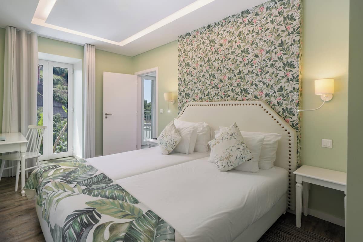 A hotel room with a large bed, a desk, and a view of the outdoors.