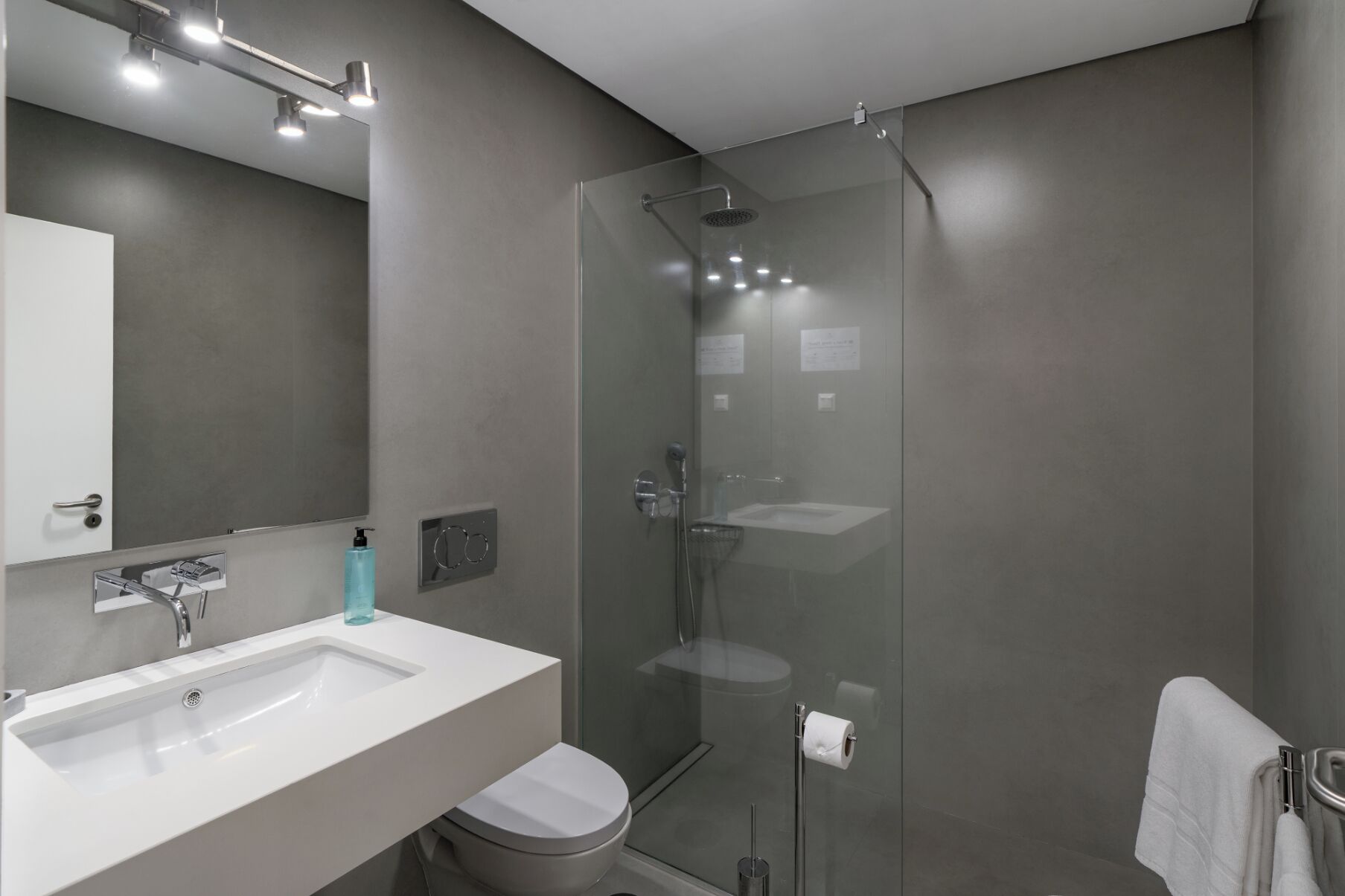 A modern bathroom with a glass-enclosed shower, a white sink, and a toilet.