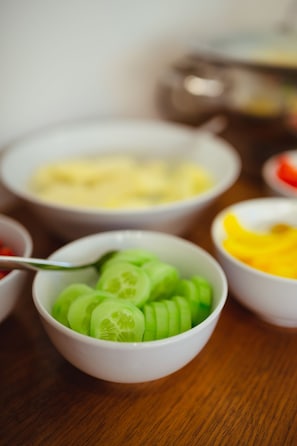 Une table sur laquelle se trouvent plusieurs bols remplis de fruits et de légumes coupés en tranches.