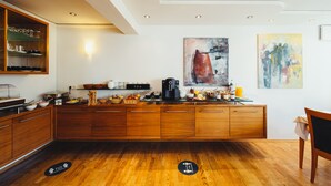Una cocina moderna con armarios de madera, una cafetera y obras de arte en las paredes.