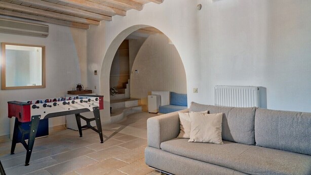 Una sala de estar acogedora con una mesa de fútbol, un sofá y una escalera que sube a un nivel superior.