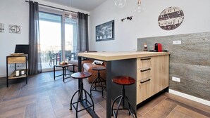 Una cocina moderna con barra, suelo de madera y un ventanal con cortinas.