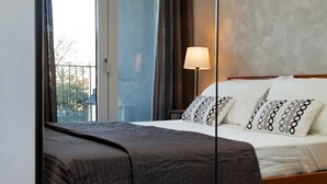 Una habitación de hotel con una cama, una mesita de noche, una lámpara y vistas al exterior.