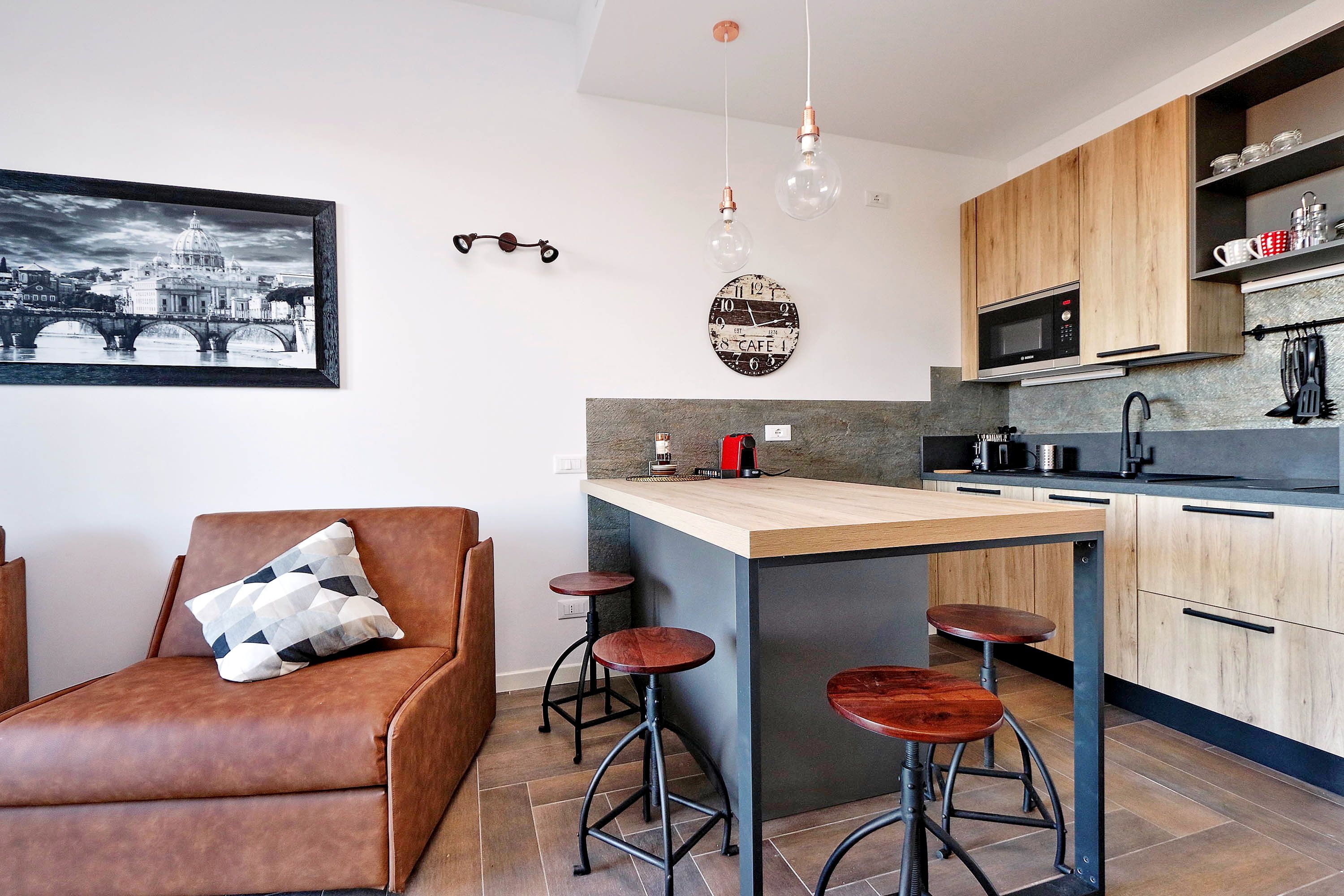 Een moderne keuken met een centraal eiland, barstoelen, een koffieapparaat en een magnetron.